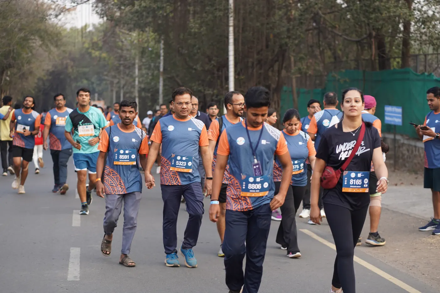 A crowd of runners and walkers in Run InSync T-shirts on the campus road