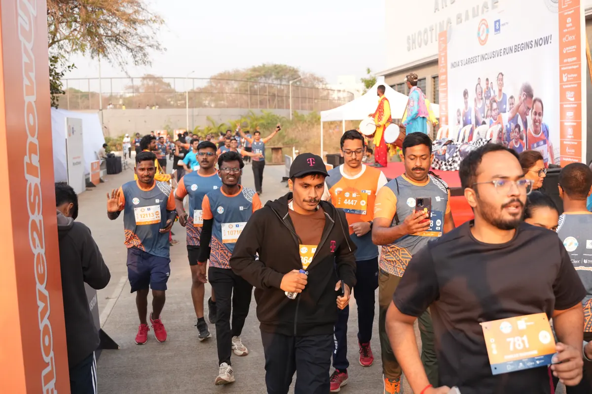 Runners sprinting towards the finish line, one holding up his bib